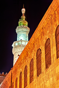Mosque tower and old stone wall in Damascus at night