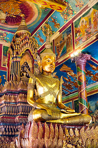 Golden Buddha statue in ornate colorful temple.
