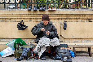 Hanoi cobbler repairs shoes on busy street in Vietnam