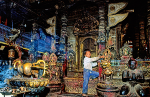 Boy interacts with religious artifacts in Kathmandu temple