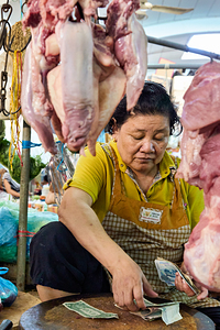 Woman vendor counting money in a meat market.