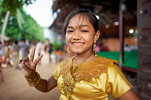Smiling girl in golden traditional dress makes peace sign.