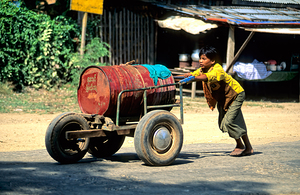 Boy pushes a cart down the street in Myanmar during the day