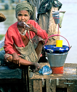 Street market scene in Yangon with a woman smoking and selling g