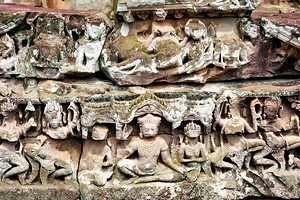 Intricate ancient stone carvings on a moss covered temple.