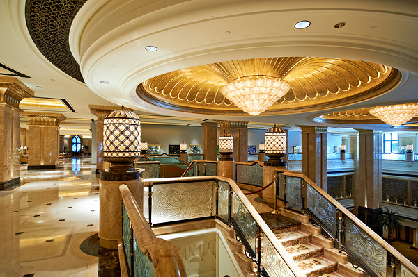 Opulent hotel lobby with grand staircase and golden chandeliers. Print