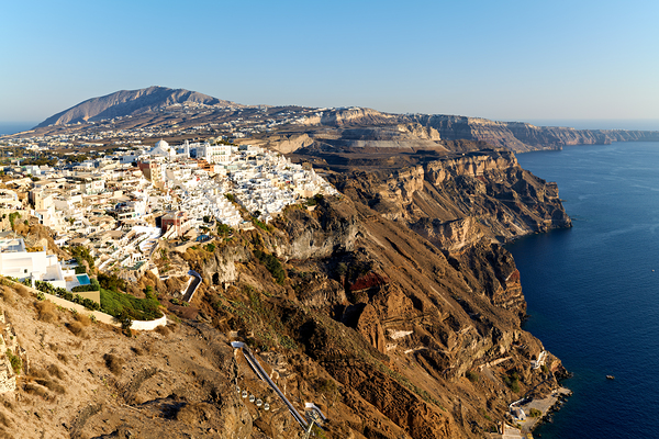 Santorinis white buildings on caldera cliffs above the sea. Print