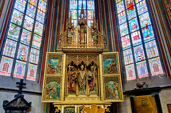 Ornate golden altarpiece and vibrant stained glass windows in a  Print