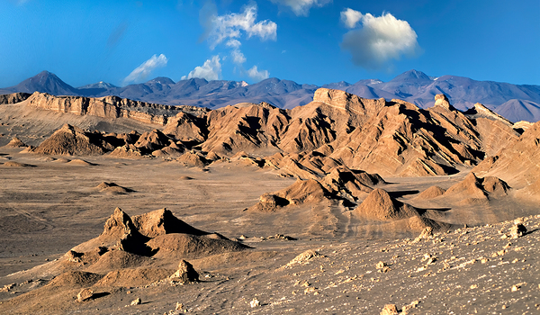 Rugged desert mountains under a clear blue sky with clouds. Print