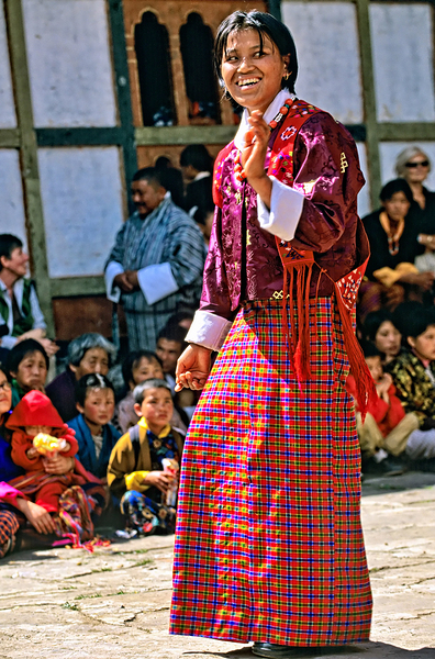 Smiling woman in vibrant Bhutanese traditional dress surrounded by Marco Brivio
