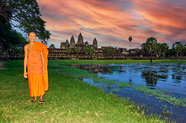 Monk stands by pond with Angkor Wat and sunset sky. Print