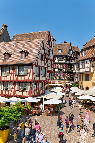 Visitors walk through Colmar on sunny day near timber framed hou Print