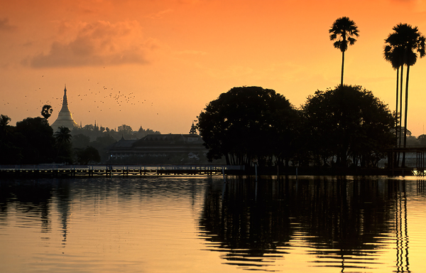 Sunset over the water in Yangon with palm trees and buildings Print