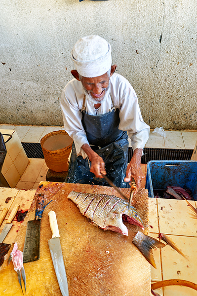 Local fisherman prepares fish at Muscat Oman fish market by Marco Brivio