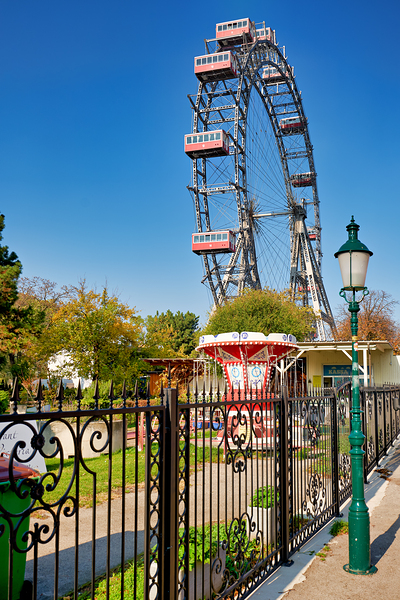Prater Ferris wheel and carousel under a clear blue sky. Print
