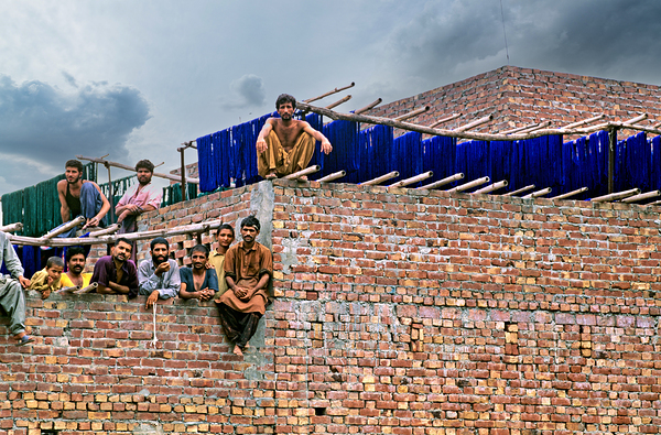Workers rest during break time at a construction site in Lahore by Marco Brivio