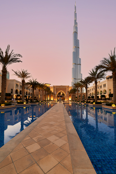 Burj Khalifa towers over pool and traditional buildings in Dubai Print