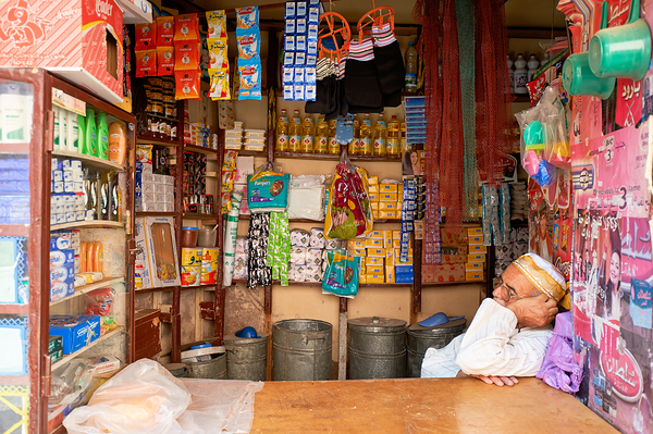 Grocer sleeping in shop in Marrakesh during afternoon hours by Marco Brivio