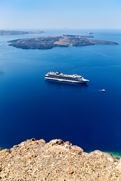 Cruise ship in deep blue sea volcanic islands rocky foreground Print