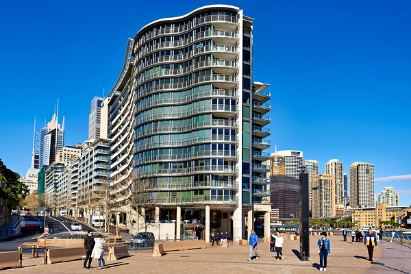 Modern curved building with balconies and city skyline. Print