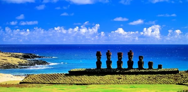 Easter Island Moai statues against a vibrant blue ocean and sky. by Marco Brivio