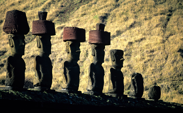 Easter Island Moai statues with red hats on a hillside. by Marco Brivio