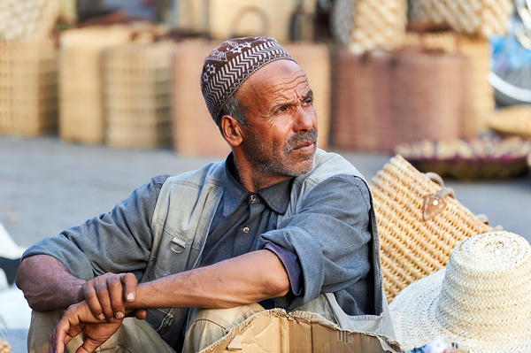 Portrait of a man in Marrakesh market selling handmade goods by Marco Brivio