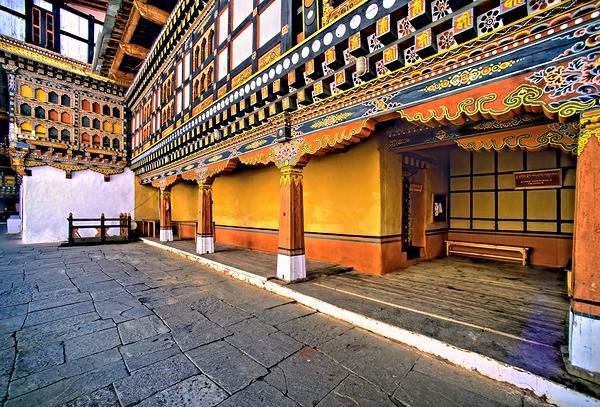 Vibrant ornate Bhutanese temple architecture and stone courtyar by Marco Brivio