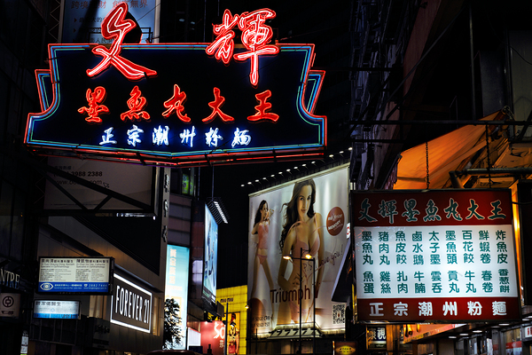 Neon signs light up a busy street in Hong Kong at night Print