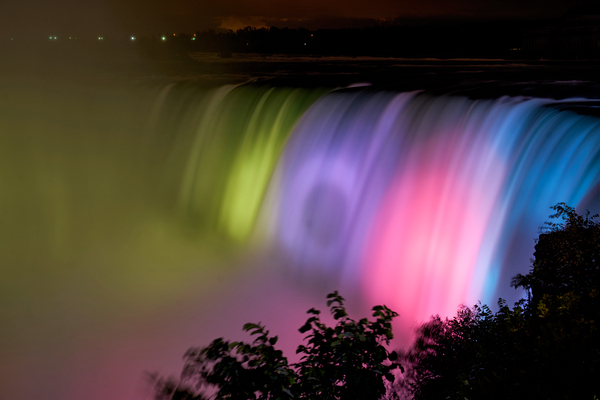 Niagara Falls illuminated with vibrant colors at night. Print