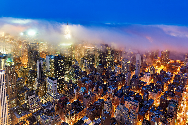 Aerial view shows Manhattan skyline at dusk with city lights Print