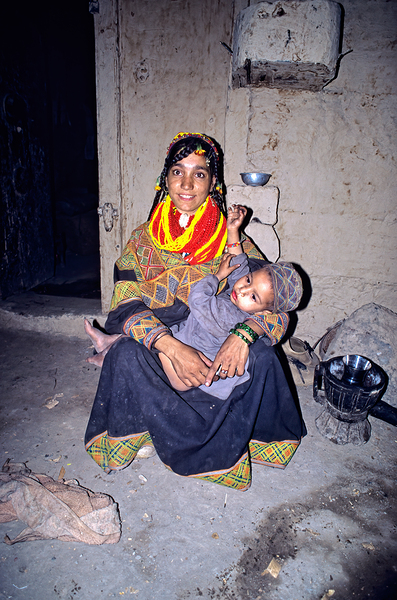A woman holds her child in a Kalash village Print