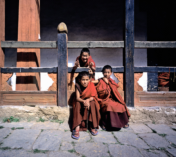 Three young monks playfully pose. by Marco Brivio