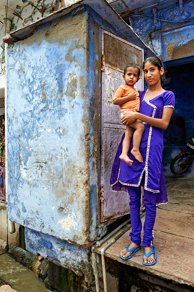Mother holds son near blue building in Bundi Rajasthan by Marco Brivio