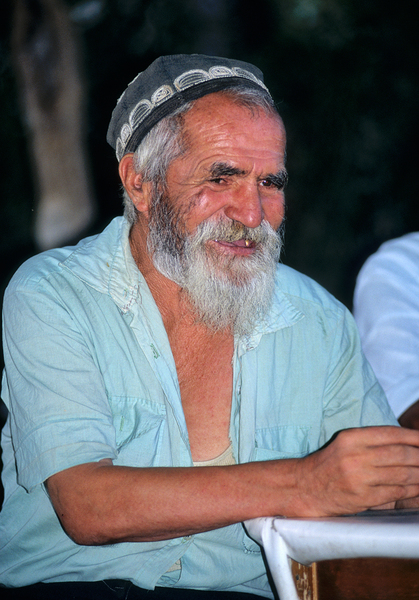 Elderly man smiles while sitting outdoors in Bukhara Uzbekistan Print