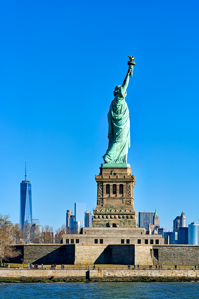 View of Statue of Liberty from Manhattan with city skyline behin by Marco Brivio