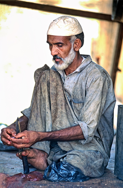 Butcher works with knife in Mingora Pakistan during day by Marco Brivio