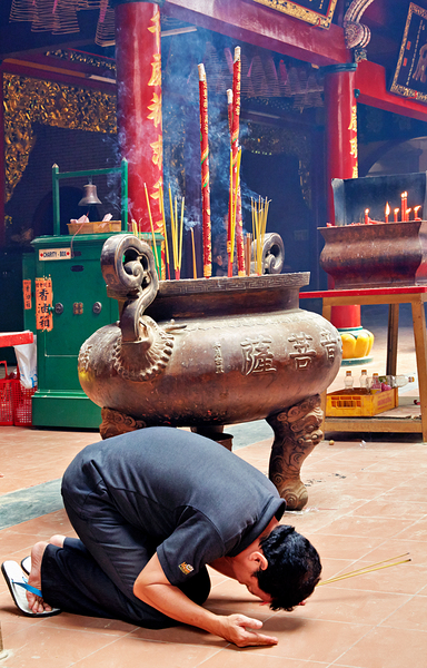 Man praying at a shrine in Ho Chi Minh City Vietnam by Marco Brivio