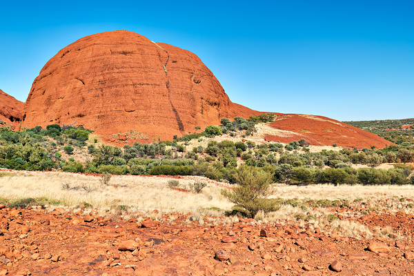 Vast red rock formation under a clear blue sky. Print