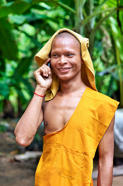 Smiling monk talks on phone with towel on head. Print