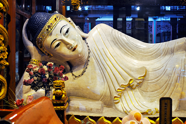 Reclining Buddha statue in Shanghai temple with flowers and gold Print