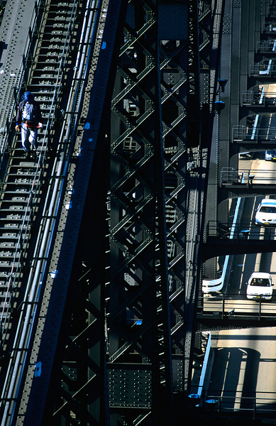 Man walks on bridge with cars below Print