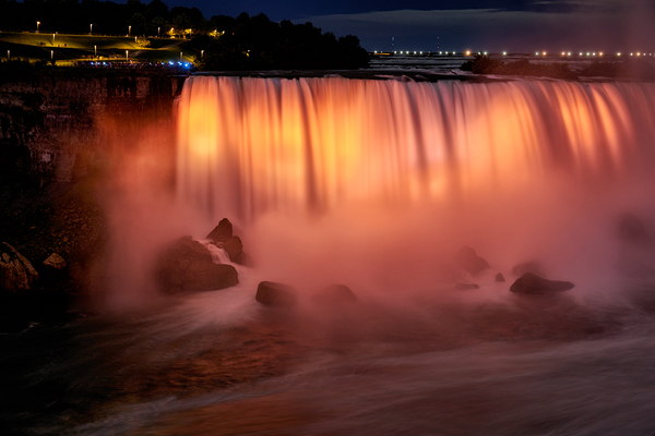 Niagara Falls illuminated orange at night. Print