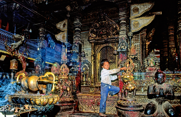 Boy interacts with religious artifacts in Kathmandu temple Print