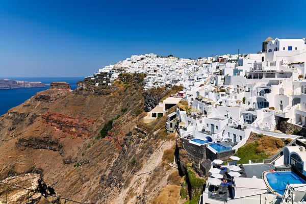 Santorini: White cliffside village blue sea clear sky. Print