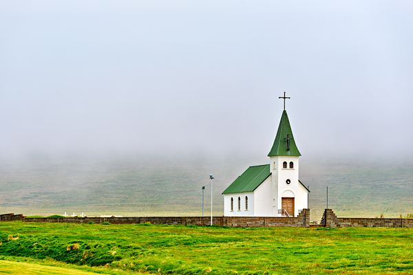 Tjarnarkirkja church stands alone in foggy landscape in Iceland by Marco Brivio
