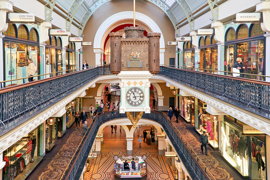 Elegant Victorian shopping arcade with clock tower and shoppers.  Print