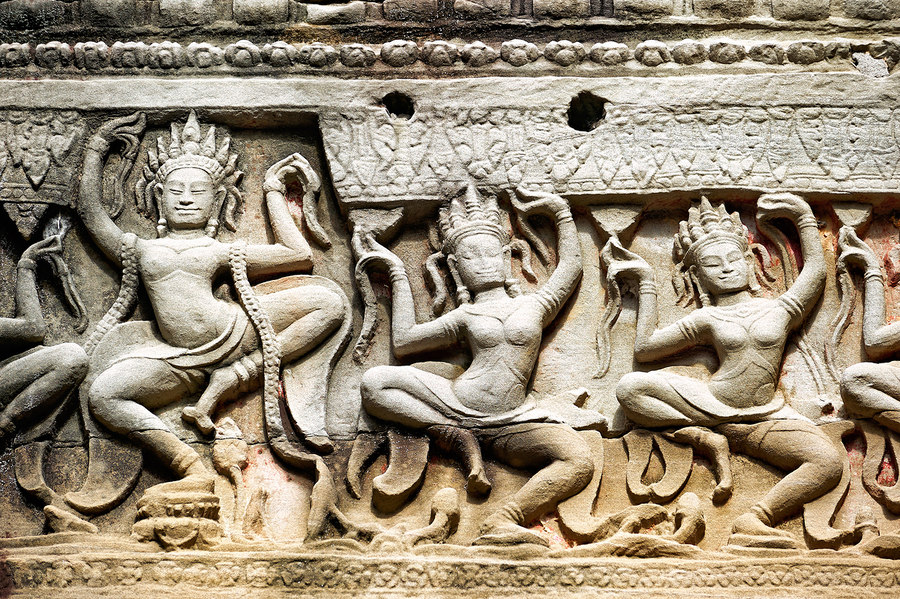 Ancient stone carvings of dancing Apsaras on a temple wall.  Print
