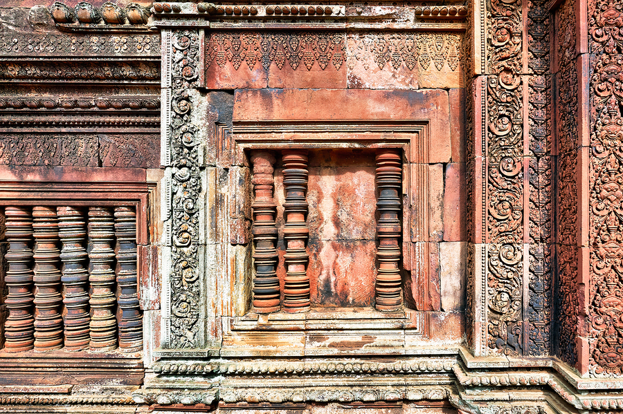 Ancient temple wall with intricate reddish stone carvings and co  Print