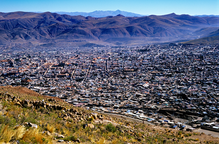 Panoramic view of a sprawling city in a mountain valley.  Print